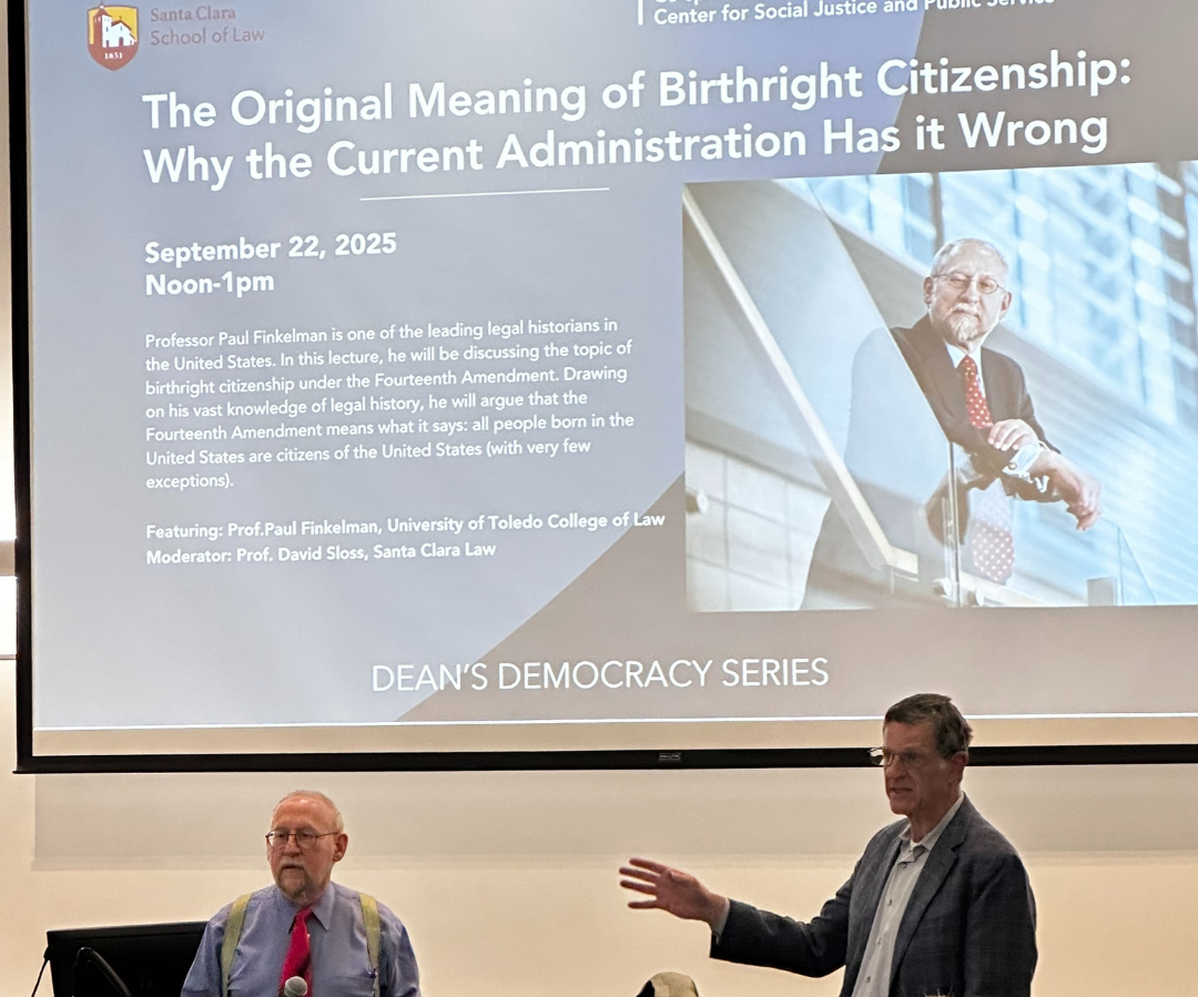 A presentation of two adult men in-front of a screen with a PowerPoint slides image link to story