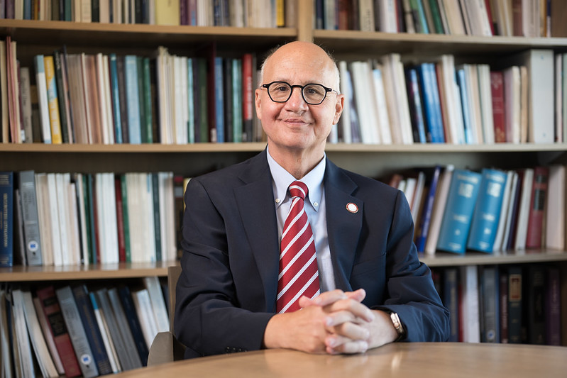 Michael Kaufman sitting at desk in front of bookshelf
