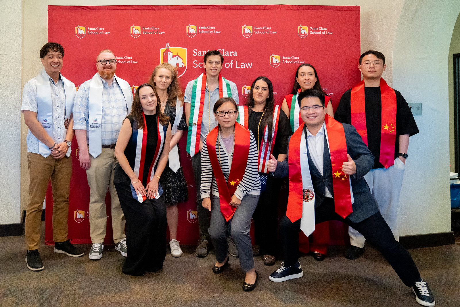 picture of students wearing graduation stoles in front of SCU Law sign