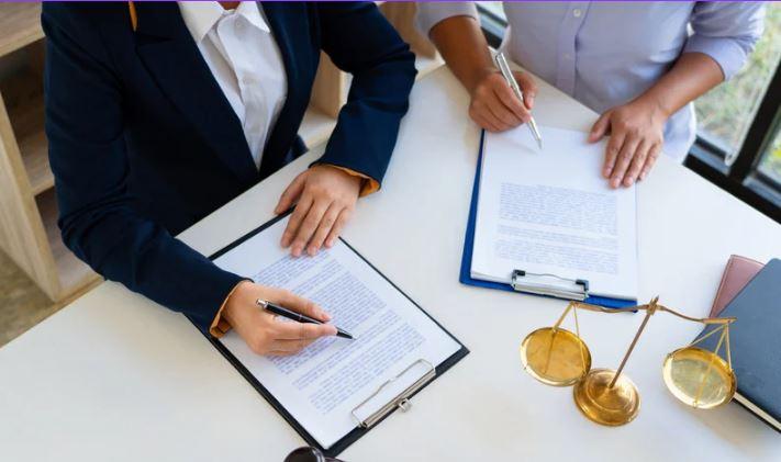 showing a desk with scales of justice and two sets of hands working on editing documents 