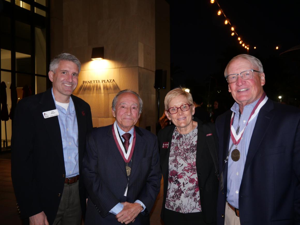 A mix of SCU leaders and two alumni wearing medals smiling.