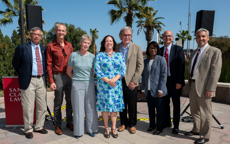 8 people standing side by side in professional clothing some are men and women at an school event 
