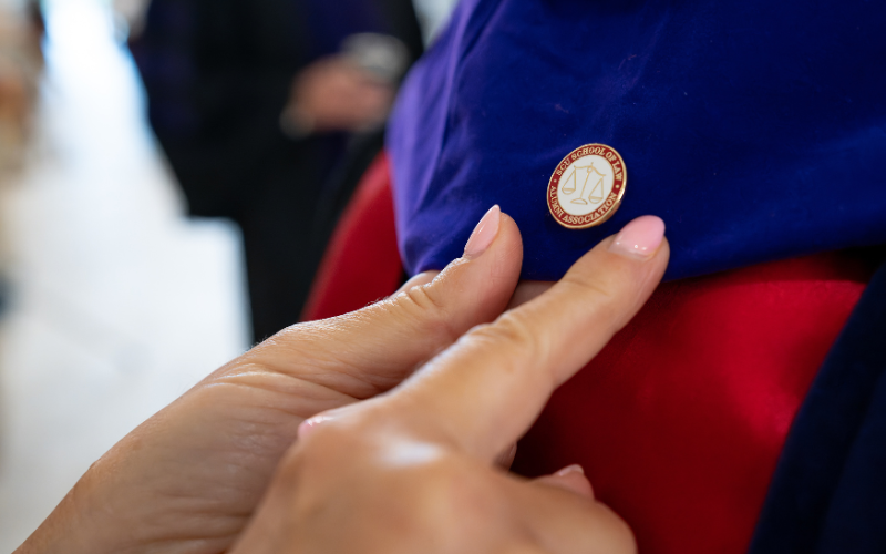 a pair of hands using their index finger to push down a pin on a blue and red hat 