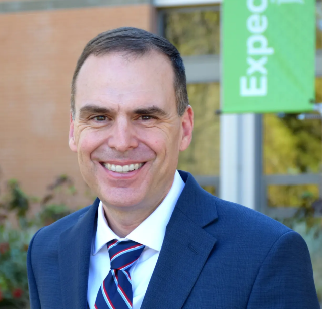 photo of prof Jeremy Weber, a white may with brown hair wearing a blue suit, white shirt and striped tie