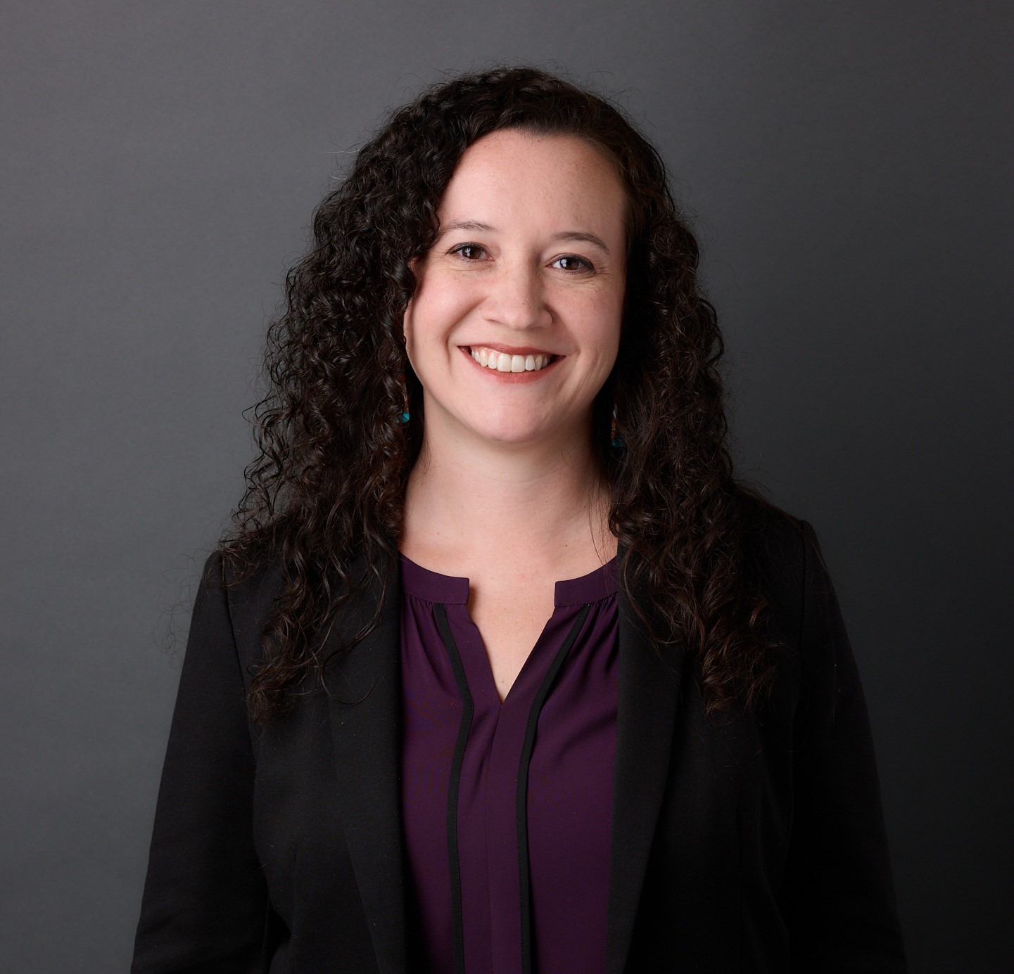 headshot of professor tania valdez a woman with curly brown hair in a purple shirt with a black blazer