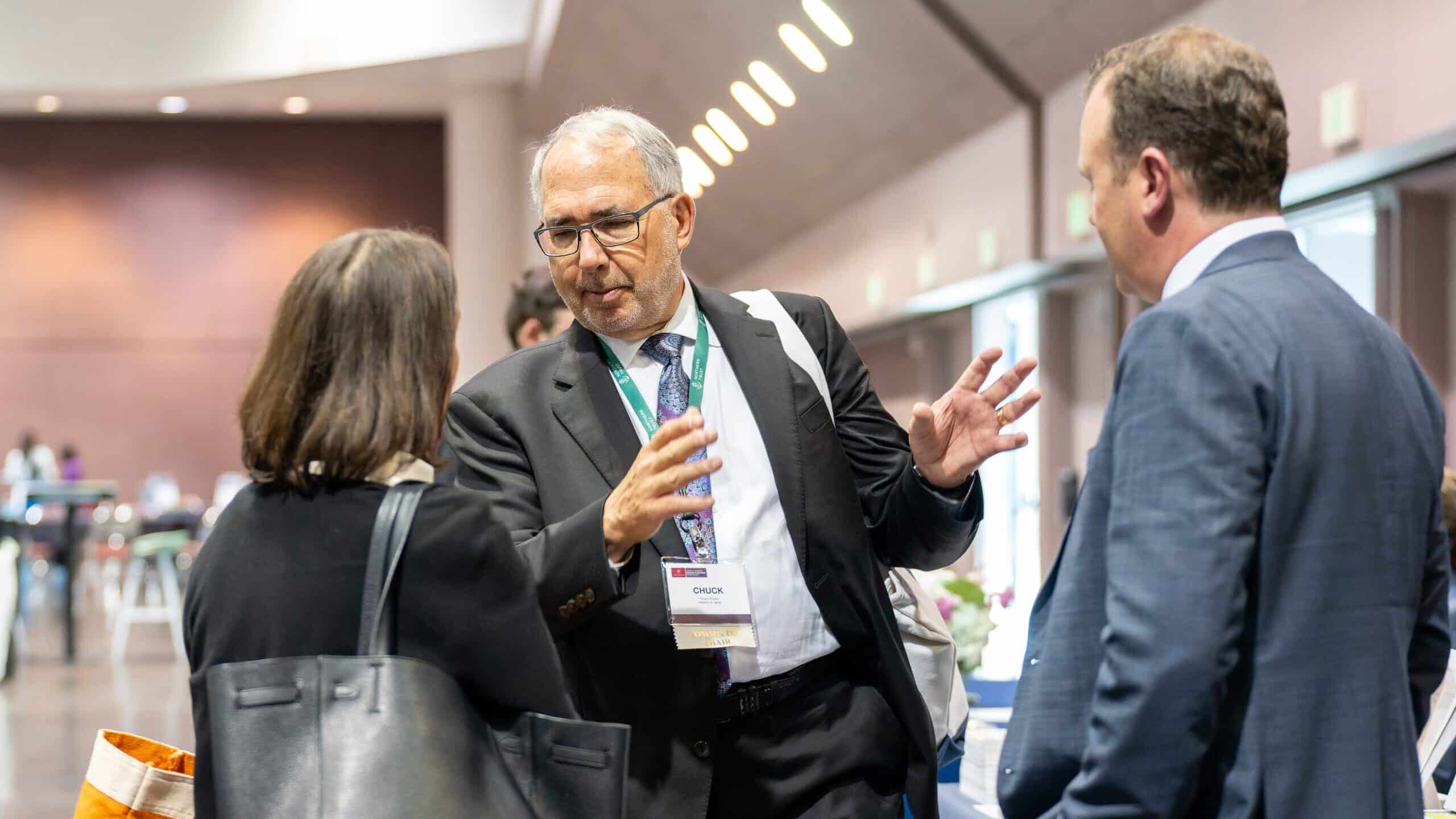 group of 3 people with event badges talking to each other in a circle at an event 