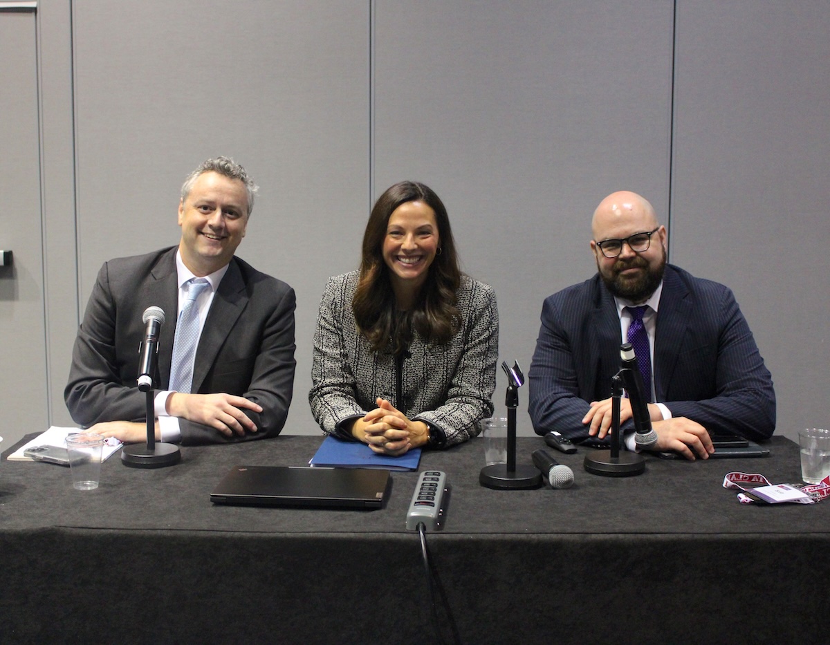two men and a woman, smiling and doing a presentation