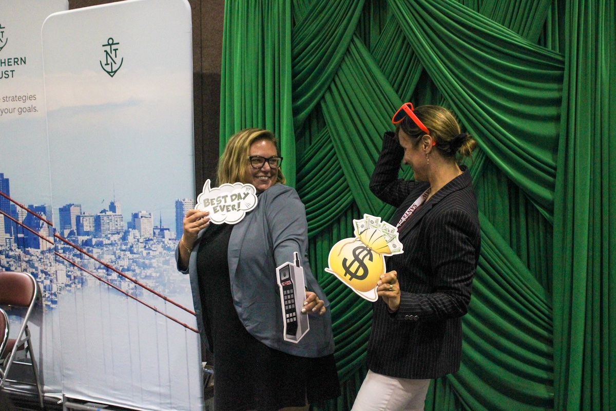 two women holding photo booth props and smiling