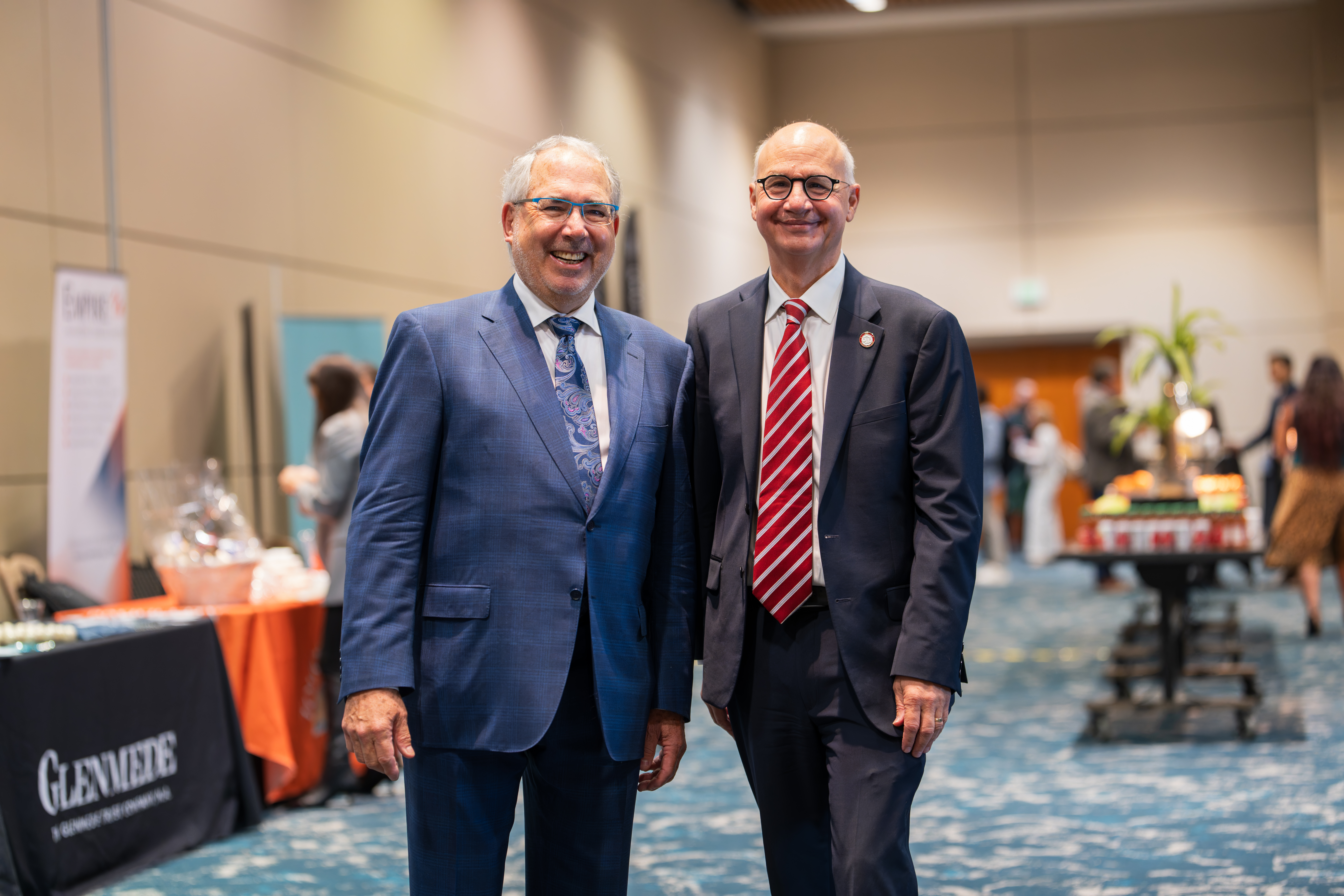 Two men in suits posing for a camera at an event