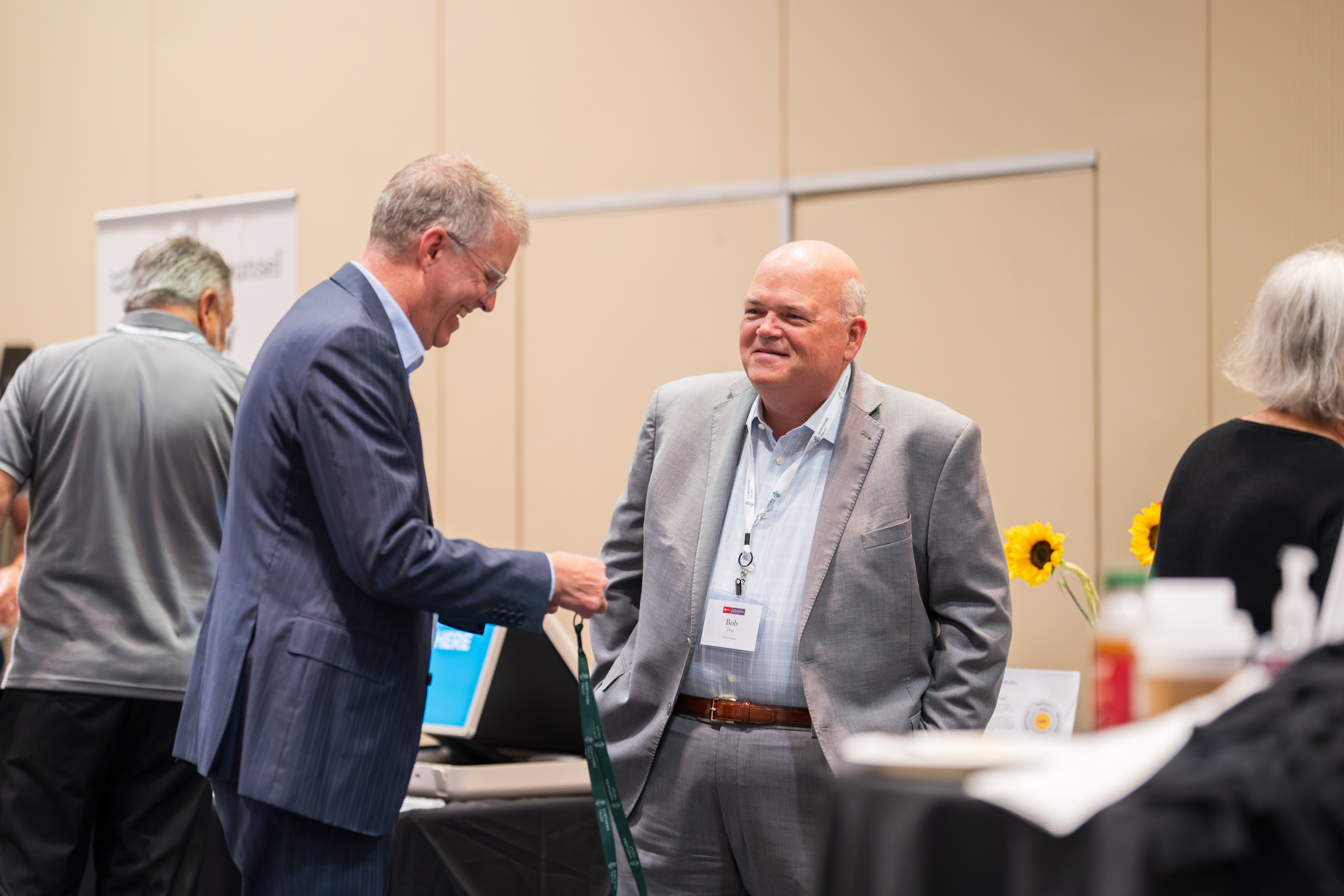 two older men in suits networking at an event.