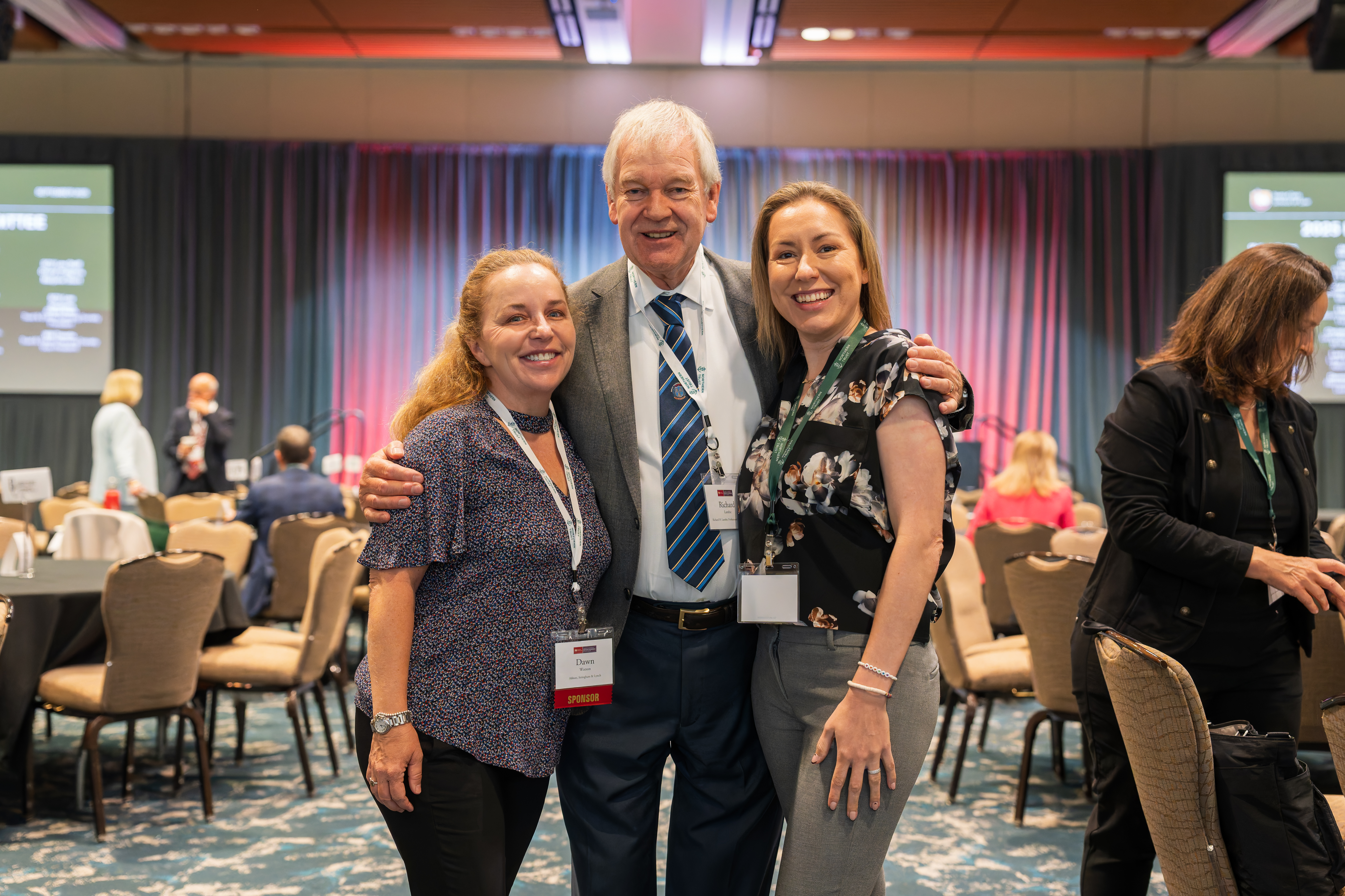 A man and two women standing and posing for the cameraman.