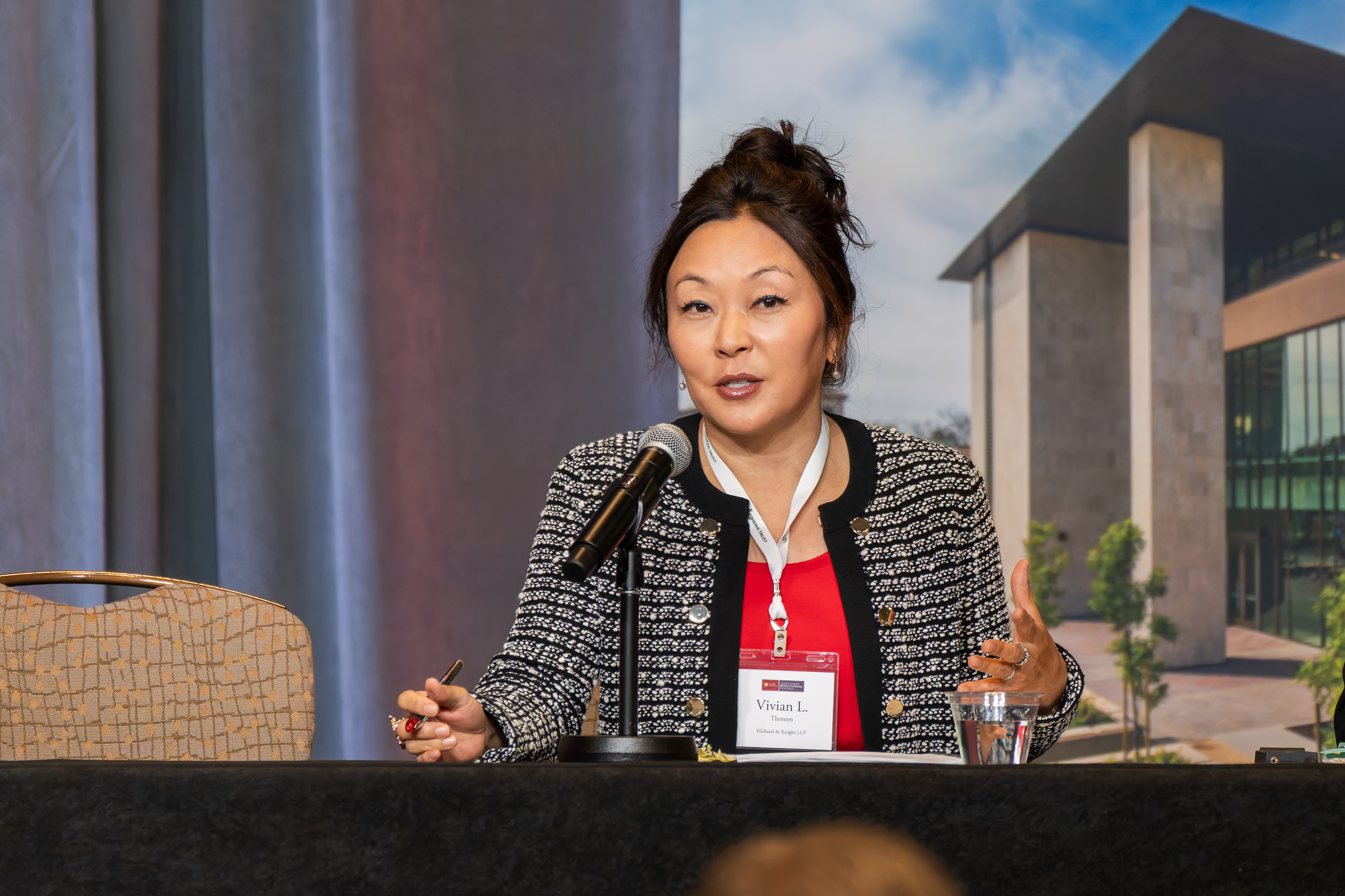 A lady on stage in front of a crowd of people speaking at an event.