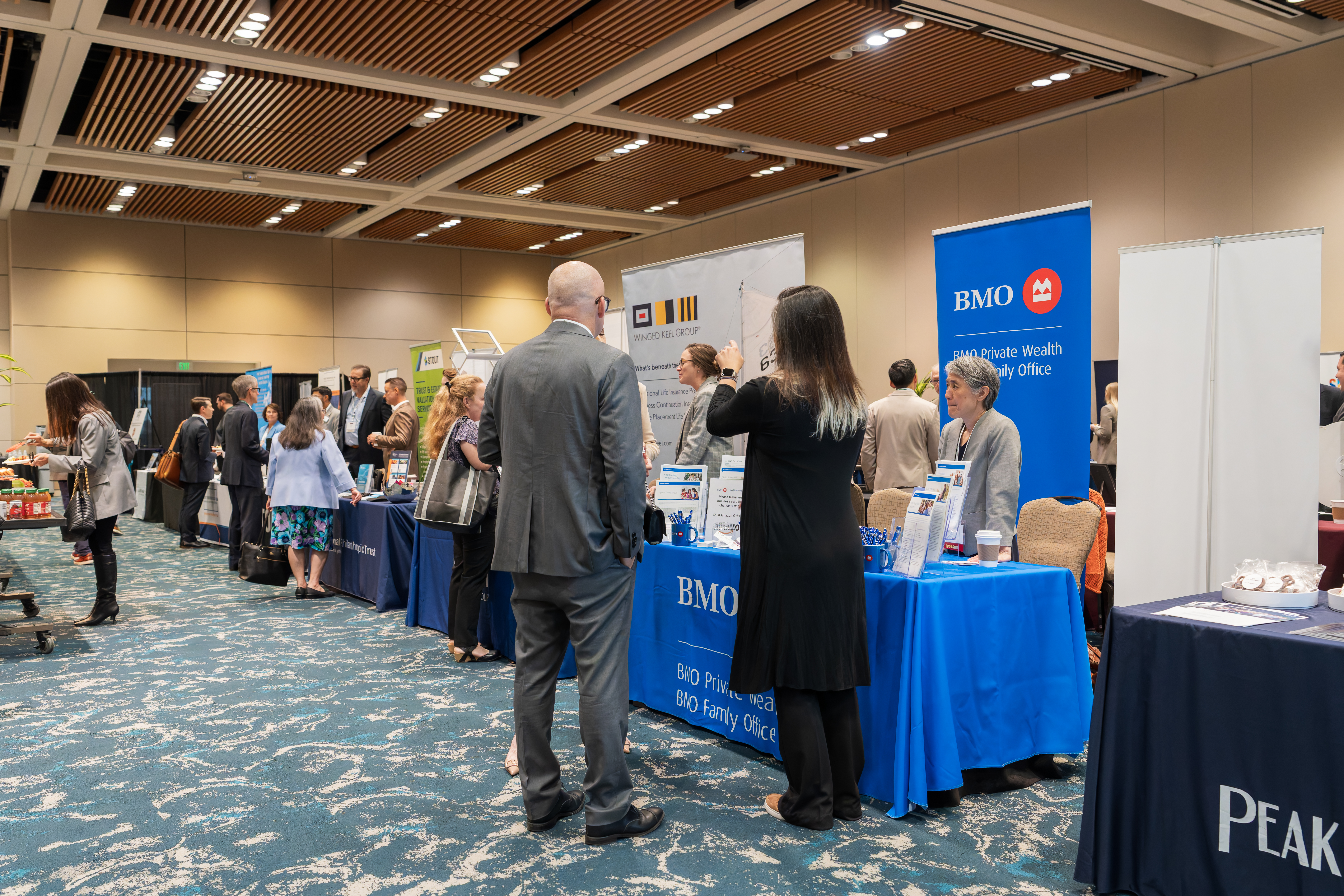 Two people standing at a booth getting information and talking to each other.