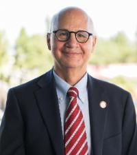 Dean Kaufman in dark suit standing on Terrace beside railing