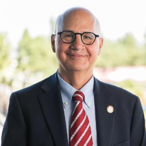 Dean Kaufman in dark suit standing on Terrace beside railing