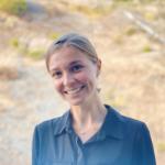 picture of law student Mary Finnegan blonde hair standing in a field, blue collared shirt and necklace