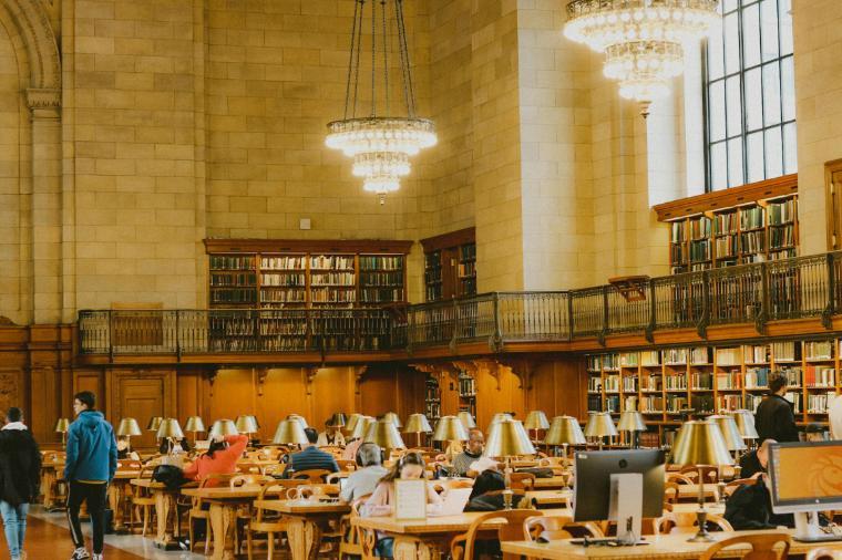 A photo of group of people at a library surrounded by a lot of books