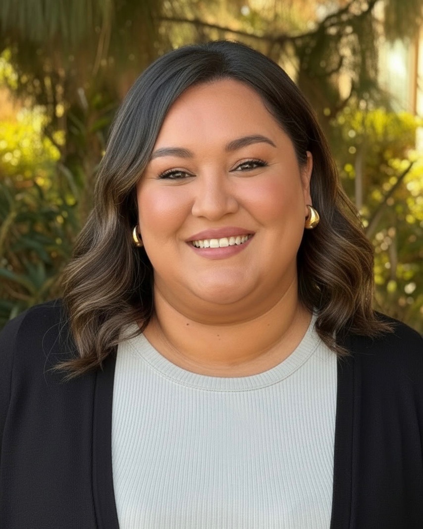 Lady with mid length hair and white shirt with black jacket smiling