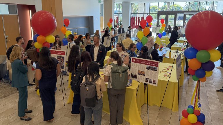 photo of the 2025 What I Did Last Summer event with tables, balloons, students and faculty members and posters of faculty scholarship activities