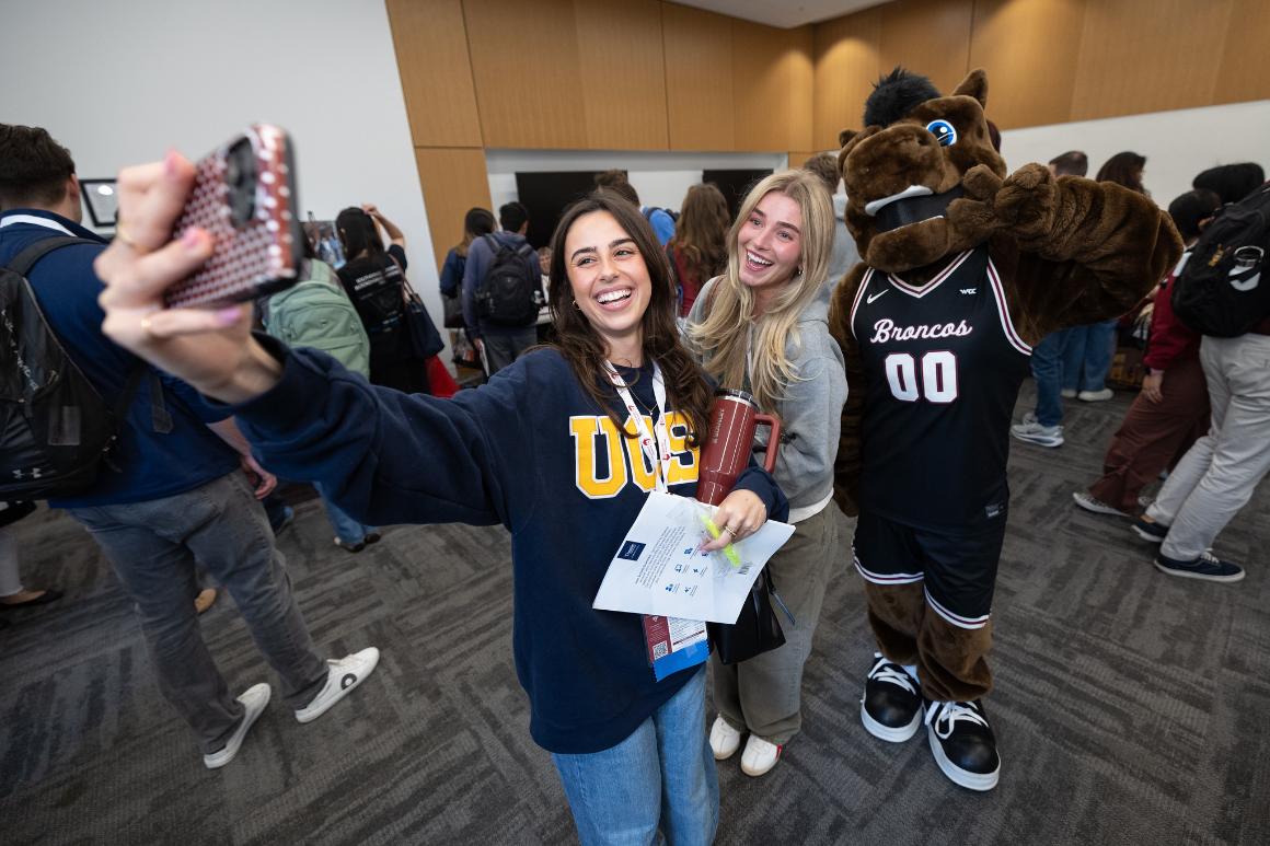 Two female students taking selfie with mascot Bucky