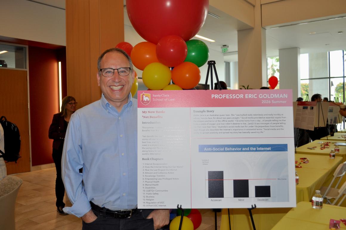 Professor Eric Goldman stands next to poster board smiling at camera