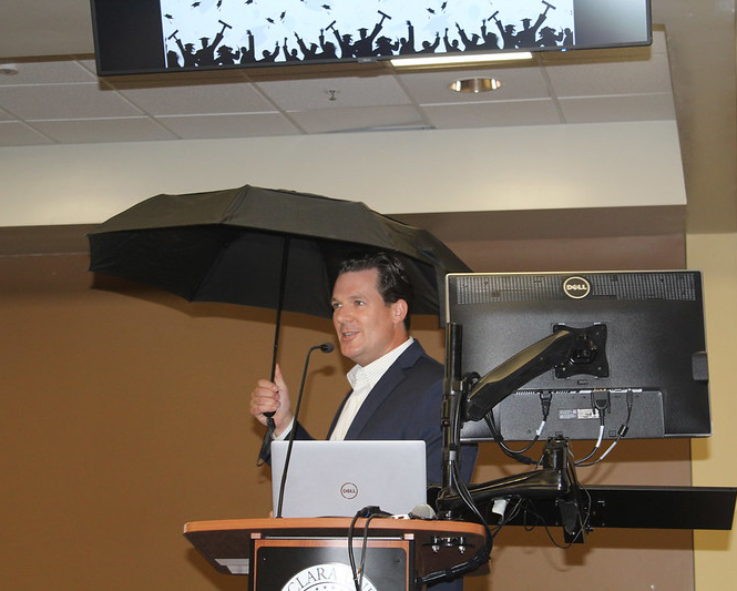 Professor Love at the Podium Under an Umbrella