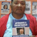Zoila Chimbo, mother of Luis Eduardo Guachalá Chimbo, with a sign that says "Help us find him"