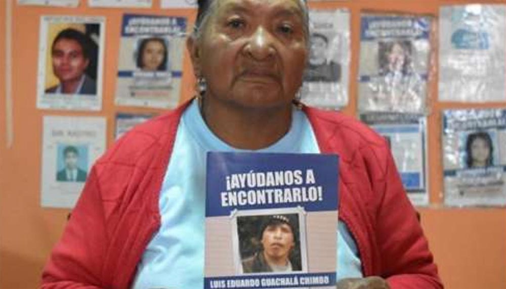 Zoila Chimbo, mother of Luis Eduardo Guachalá Chimbo, with a sign that says "Help us find him"